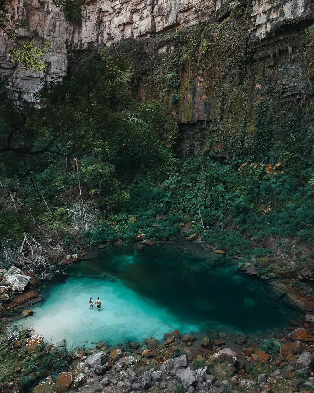 vista superior do santuario das araras. A agua está na tonalidade verde e tem um casal entrando na água.