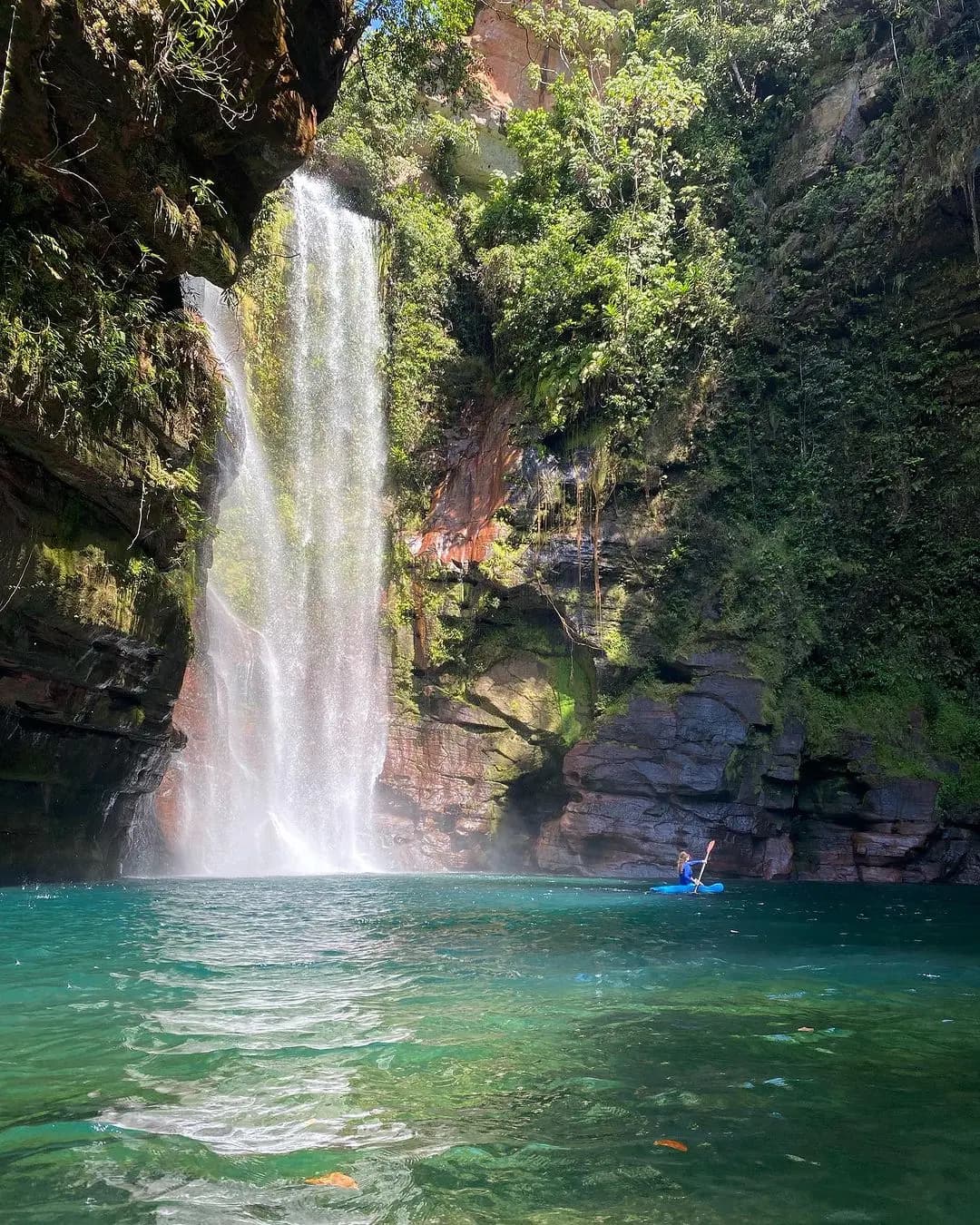 cachoeira azul com uma pessoa de caiaque no lado direito